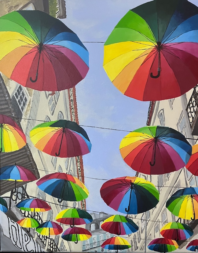 A painting of rainbow umbrellas hanging from string overhead between two building.
