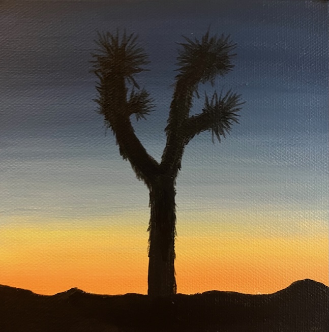A Joshua tree is silhouetted against a fading sunset. The sky fades from dark blue on the top to light orange before reaching the dark ground 